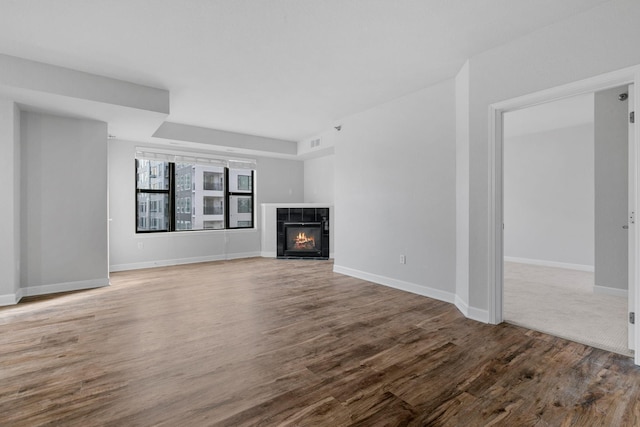 unfurnished living room featuring a tile fireplace and hardwood / wood-style floors