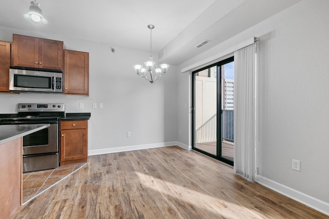 kitchen featuring appliances with stainless steel finishes, an inviting chandelier, light wood-type flooring, and decorative light fixtures