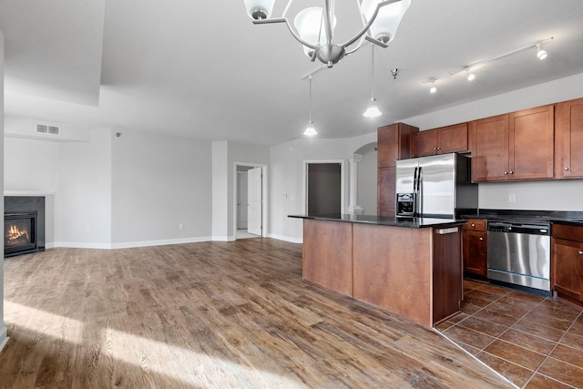 kitchen featuring a center island, appliances with stainless steel finishes, dark hardwood / wood-style floors, a notable chandelier, and pendant lighting