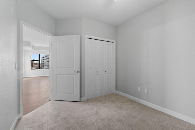 unfurnished bedroom with light carpet and a closet