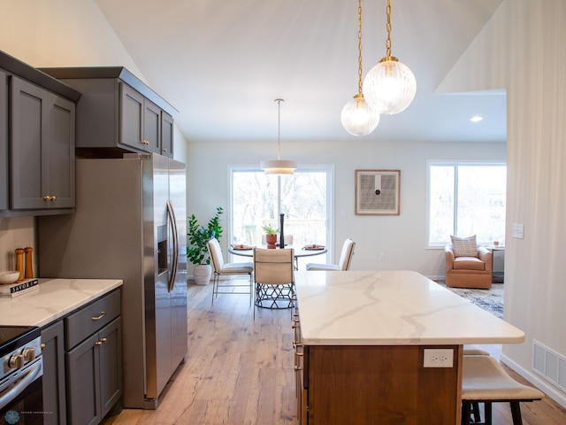 kitchen with pendant lighting, a center island, light stone counters, and light hardwood / wood-style flooring