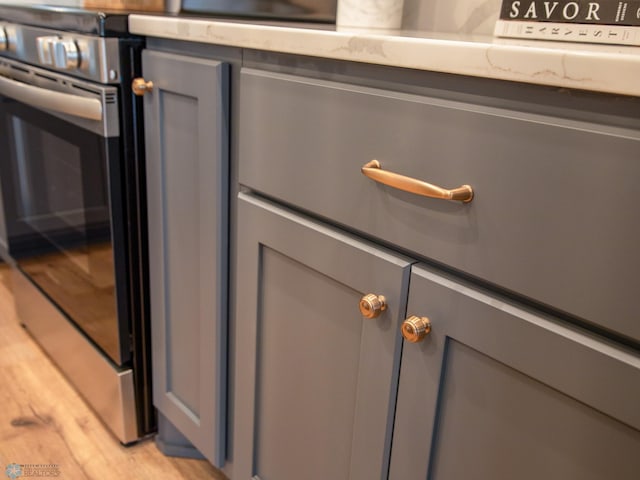 interior details featuring gray cabinets, stainless steel stove, and light hardwood / wood-style floors