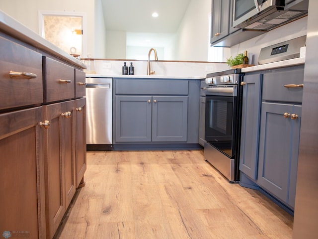 kitchen featuring appliances with stainless steel finishes, light hardwood / wood-style floors, and sink