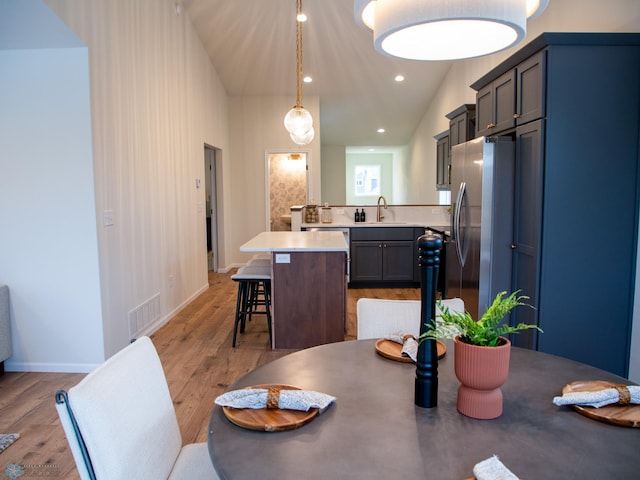 dining space featuring high vaulted ceiling, light hardwood / wood-style flooring, and sink