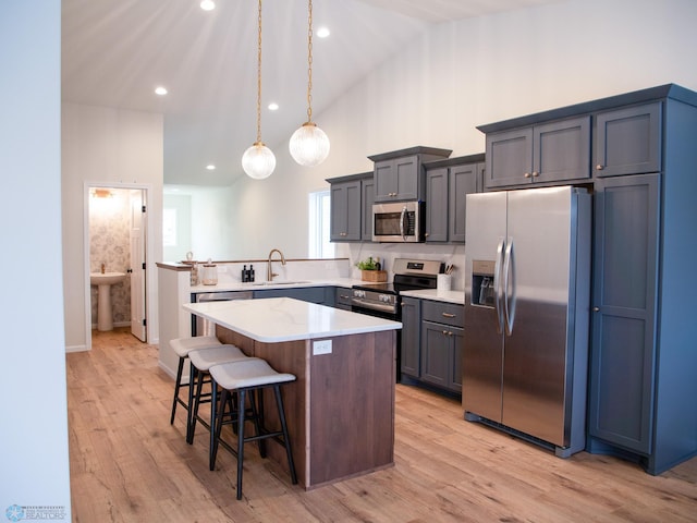 kitchen with sink, hanging light fixtures, a breakfast bar area, a kitchen island, and stainless steel appliances