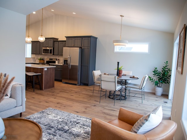 living room with light wood-type flooring, plenty of natural light, and lofted ceiling