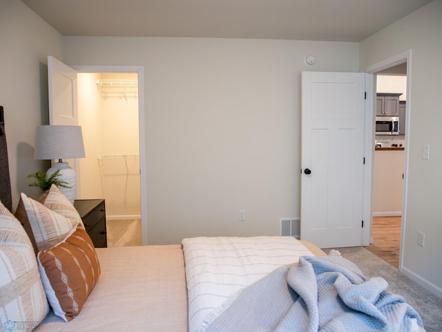 bedroom featuring light colored carpet, a walk in closet, and a closet