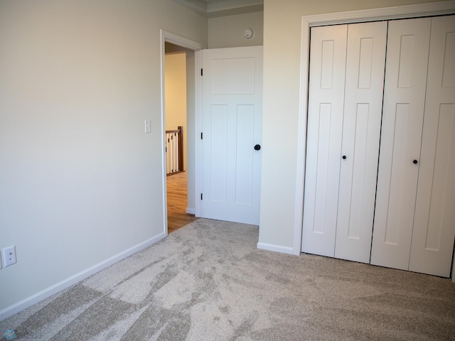 unfurnished bedroom featuring a closet and light colored carpet