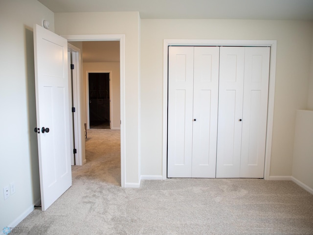 unfurnished bedroom with light colored carpet and a closet