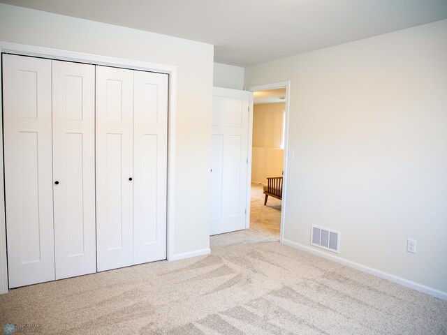 unfurnished bedroom featuring a closet and light colored carpet