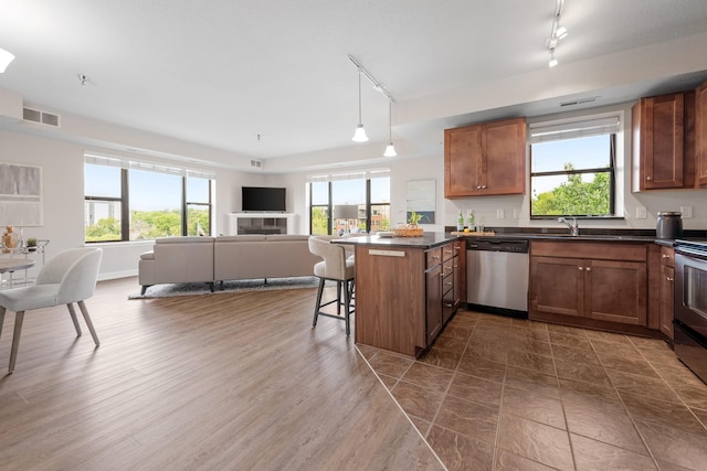 kitchen with stainless steel dishwasher, a kitchen bar, kitchen peninsula, and a wealth of natural light