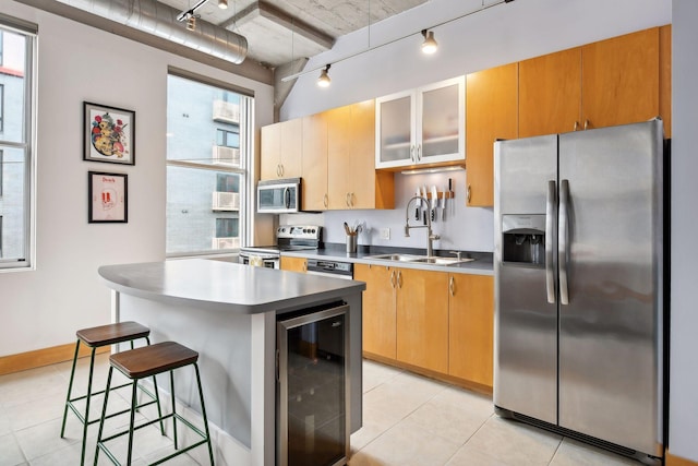 kitchen featuring sink, wine cooler, a kitchen bar, a kitchen island, and appliances with stainless steel finishes