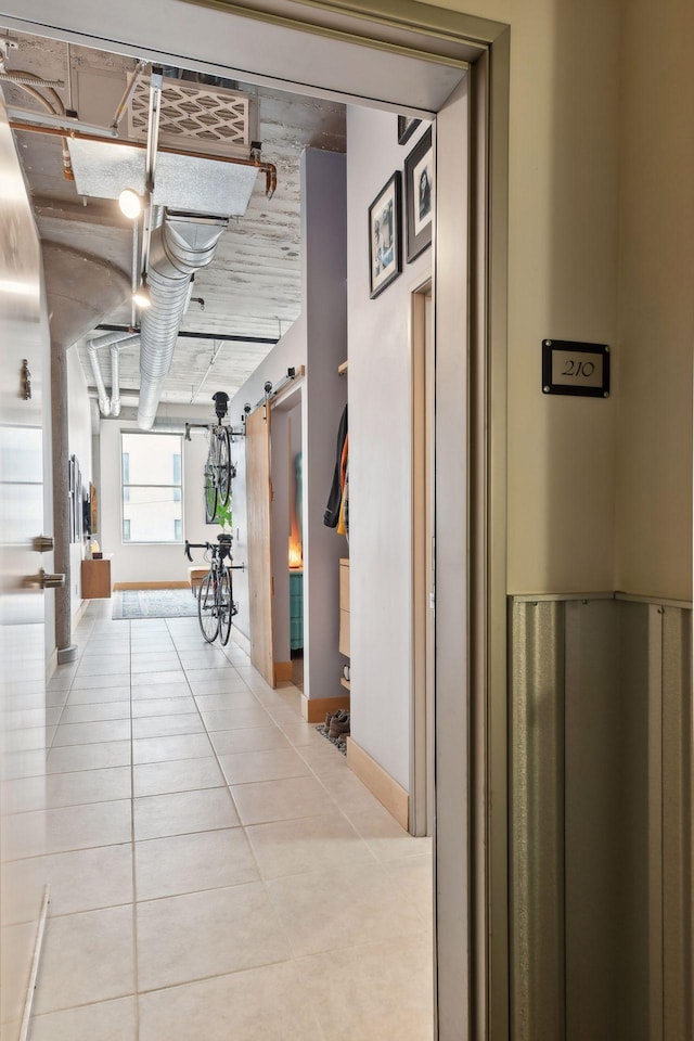 hallway featuring light tile patterned floors and a barn door