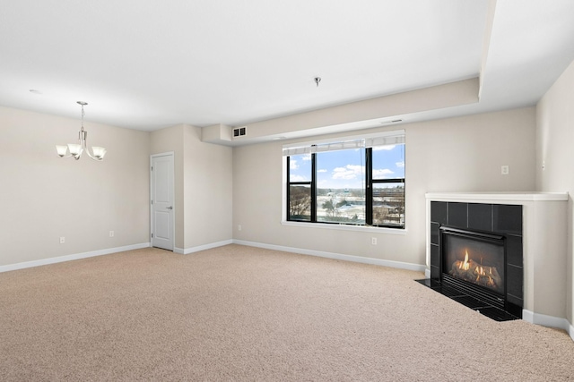 unfurnished living room with light colored carpet, a tile fireplace, and a notable chandelier