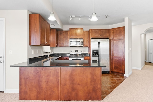 kitchen with sink, hanging light fixtures, track lighting, appliances with stainless steel finishes, and kitchen peninsula