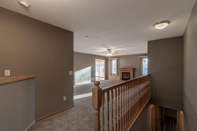 hall with a textured ceiling and carpet floors