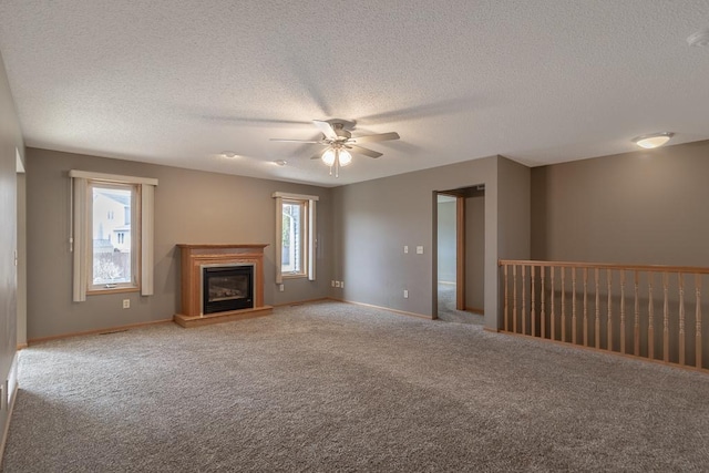 1733 Bassett Dr, Mankato, MN 56001 - unfurnished living room featuring ceiling fan, carpet, a glass covered fireplace, and a healthy amount of sunlight