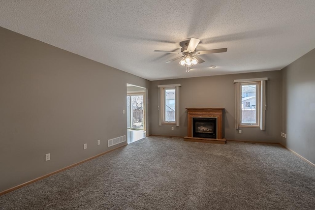 1733 Bassett Dr, Mankato, MN 56001 - unfurnished living room with a glass covered fireplace, visible vents, a ceiling fan, and a healthy amount of sunlight