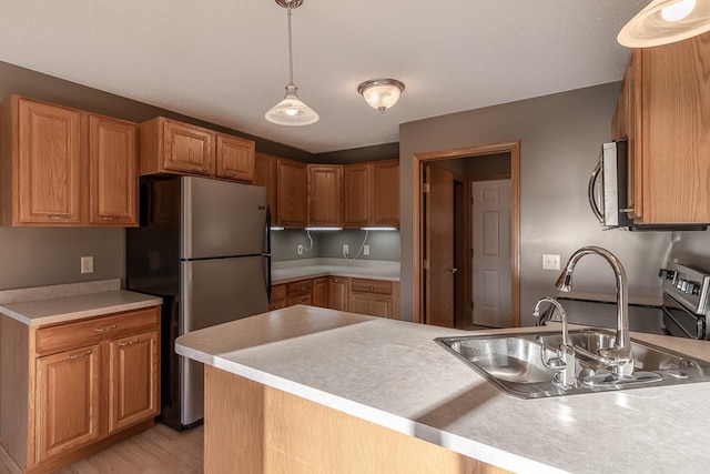 1733 Bassett Dr, Mankato, MN 56001 - kitchen featuring a peninsula, light countertops, appliances with stainless steel finishes, a sink, and hanging light fixtures