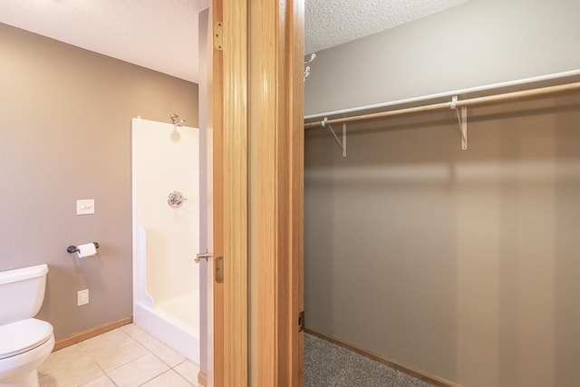 1733 Bassett Dr, Mankato, MN 56001 - full bathroom featuring baseboards, toilet, a textured ceiling, a shower stall, and tile patterned floors