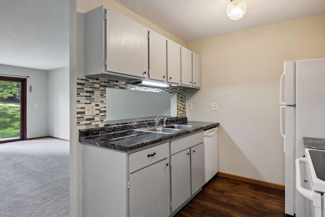 kitchen with tasteful backsplash, dark carpet, a textured ceiling, white appliances, and sink