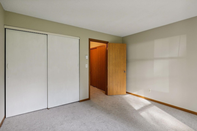 unfurnished bedroom featuring a closet and light colored carpet