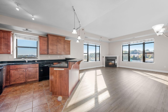 kitchen with sink, a kitchen breakfast bar, black dishwasher, a kitchen island, and decorative light fixtures