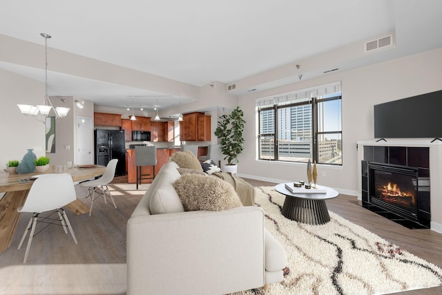 living room featuring light hardwood / wood-style flooring, a tile fireplace, and track lighting