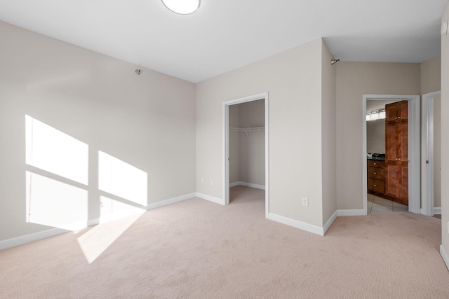 unfurnished bedroom featuring a walk in closet, light colored carpet, and a closet