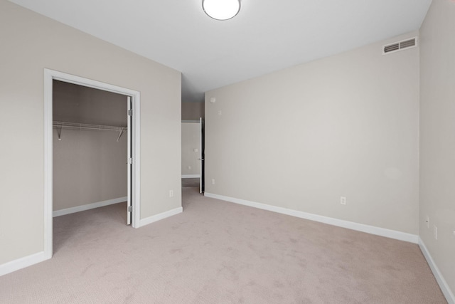 unfurnished bedroom featuring light carpet, a walk in closet, and a closet