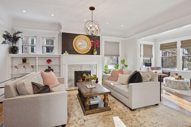 living room featuring a high end fireplace, light hardwood / wood-style floors, a wealth of natural light, and a notable chandelier