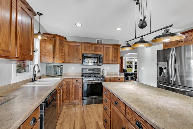 kitchen with pendant lighting, sink, light hardwood / wood-style flooring, and stainless steel appliances