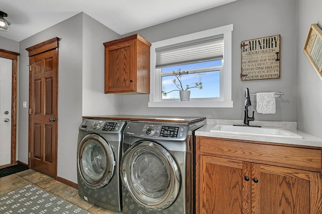 clothes washing area featuring cabinets, sink, and washer and clothes dryer