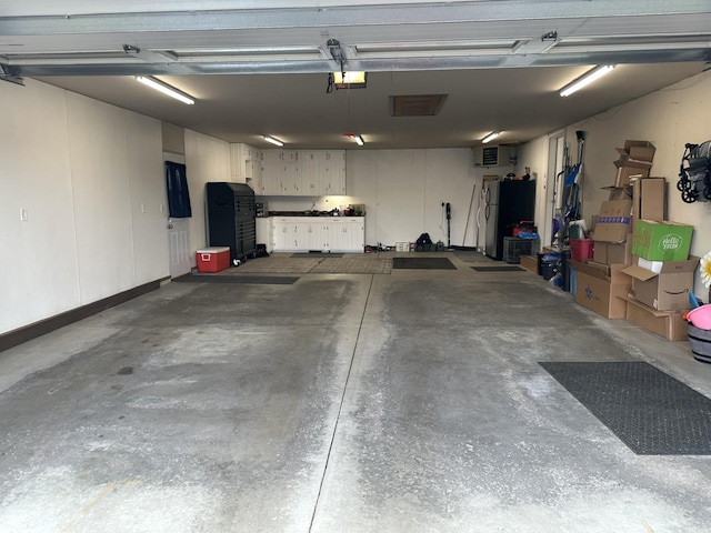 garage with a garage door opener and stainless steel refrigerator