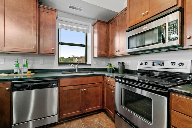 kitchen with sink, stainless steel appliances, and dark tile patterned flooring