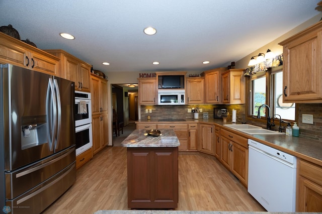 kitchen featuring a kitchen island, sink, decorative backsplash, white appliances, and light hardwood / wood-style flooring