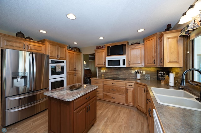 kitchen with sink, decorative backsplash, a center island, white appliances, and light hardwood / wood-style flooring