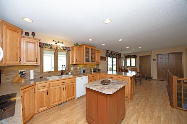 kitchen featuring sink, a center island, light wood-type flooring, dishwasher, and kitchen peninsula