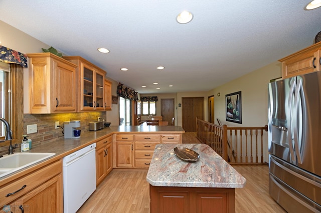 kitchen with sink, stainless steel fridge, dishwasher, a center island, and kitchen peninsula