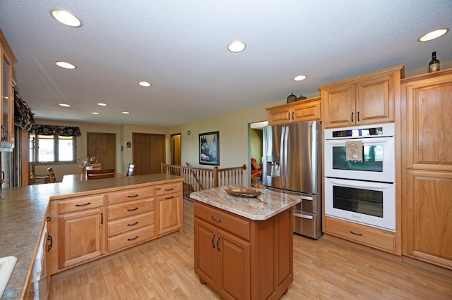 kitchen featuring a kitchen island, white double oven, stainless steel fridge with ice dispenser, a textured ceiling, and light hardwood / wood-style flooring