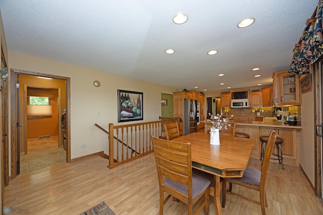 dining room with light hardwood / wood-style flooring and a textured ceiling