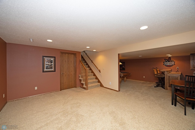 basement featuring light carpet and a textured ceiling