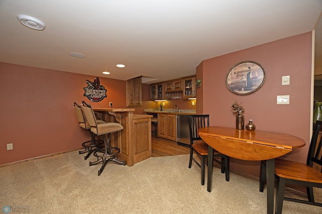 bar with stainless steel dishwasher, sink, and light carpet