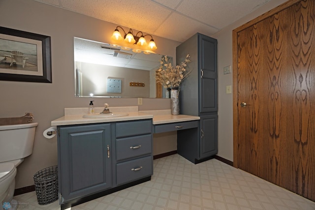 bathroom with vanity, toilet, and a drop ceiling