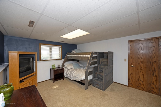 bedroom featuring light colored carpet and a drop ceiling