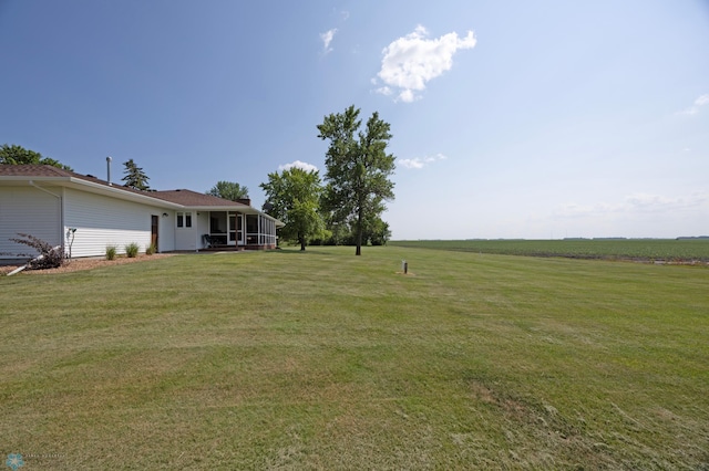 view of yard featuring a sunroom and a rural view