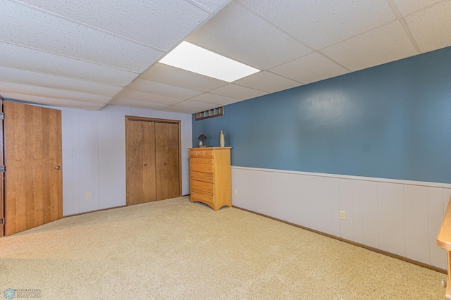 unfurnished bedroom featuring a drop ceiling, carpet floors, and a closet