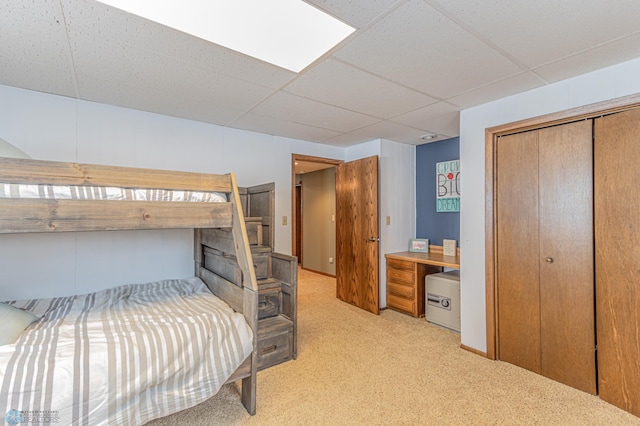 carpeted bedroom featuring a drop ceiling and a closet