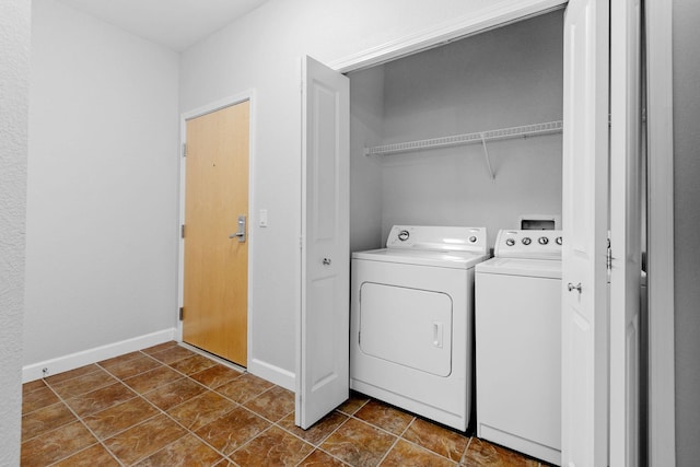 washroom with washer and clothes dryer and dark tile patterned flooring