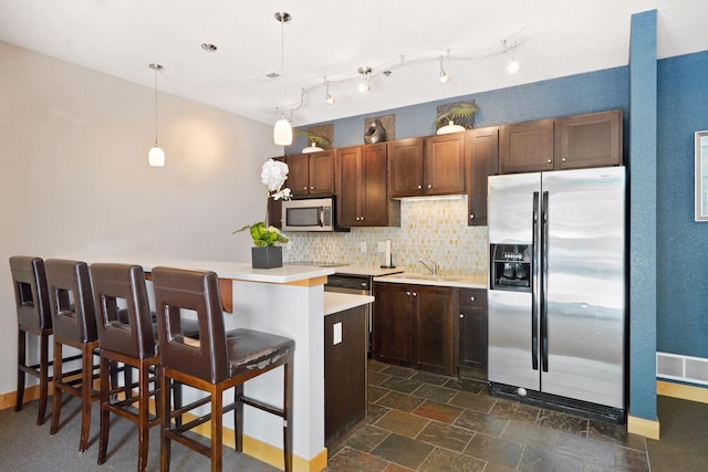 kitchen with sink, a breakfast bar area, hanging light fixtures, stainless steel appliances, and tasteful backsplash